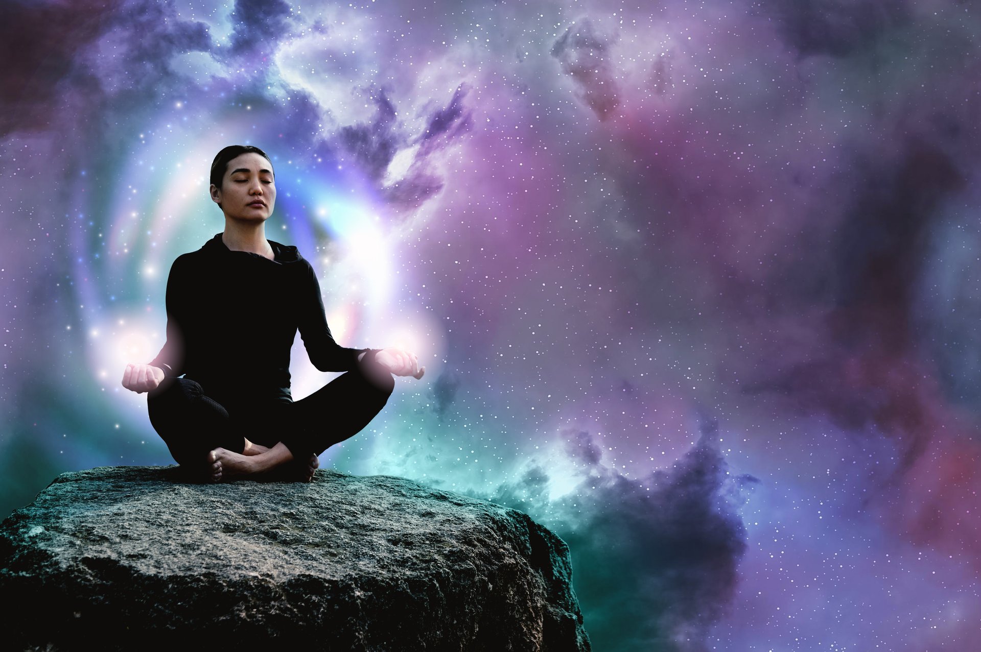 Mujer meditando sobre una roca frente a un fondo de estrellas y colores cósmicos.