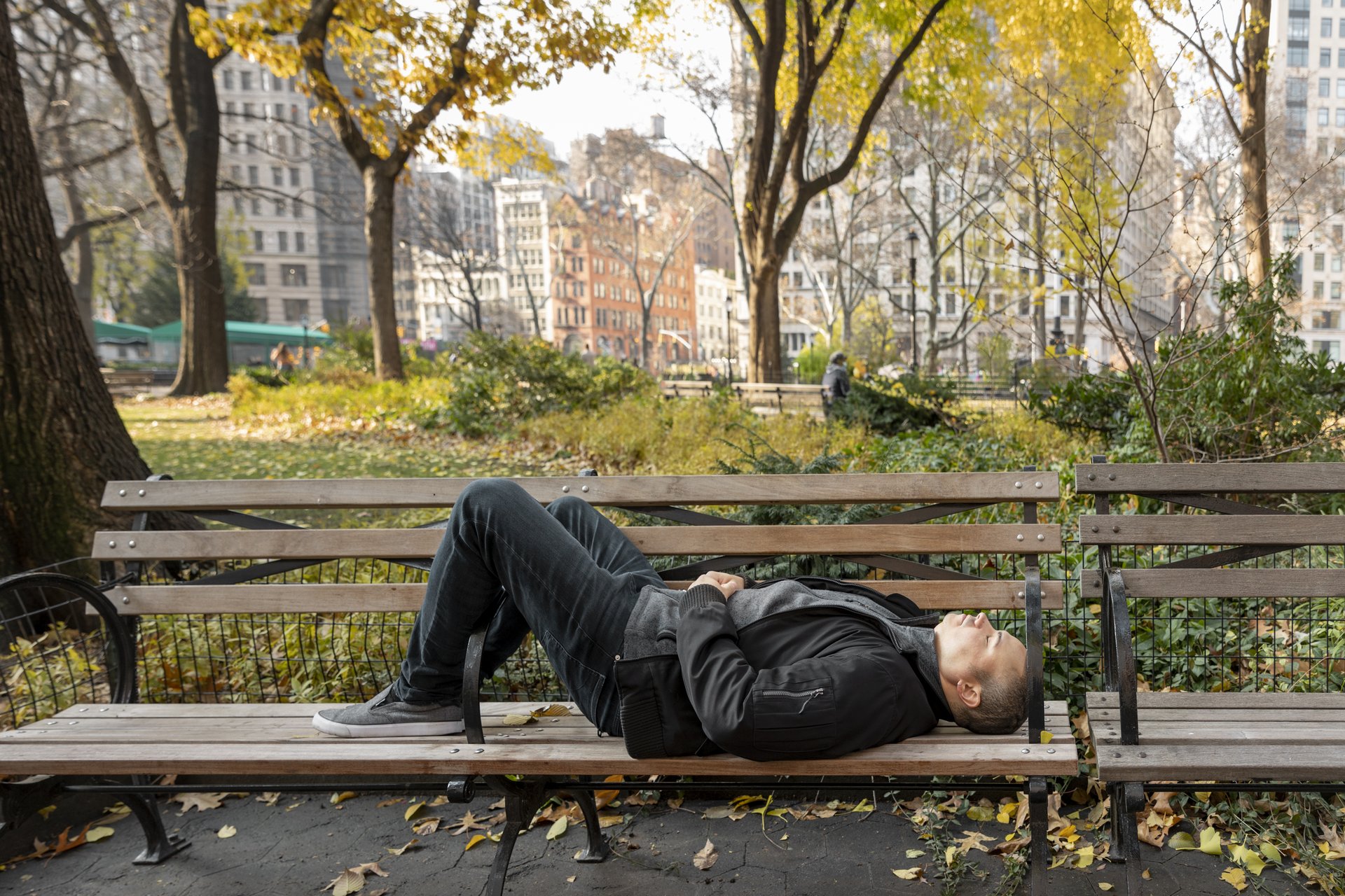 recuperar-cuerpo-despues-caminar-madrid Hombre descansando tumbado en un banco de un parque de Madrid después de caminar.